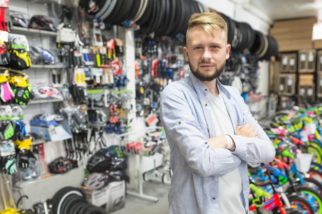 Mechanic with folded arms standing in bicycle workshop