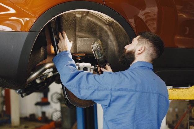 Foto gratuita meccanico con uno strumento. ruota nelle mani di un meccanico. abiti da lavoro blu.