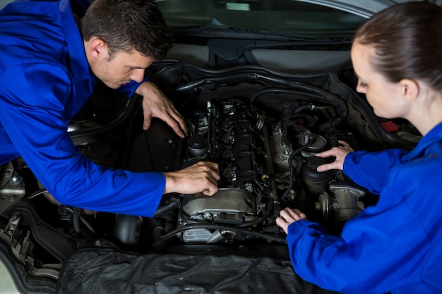 Mechanics examining car engine