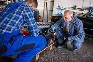 Foto gratuita meccanici che riparano un'auto in officina