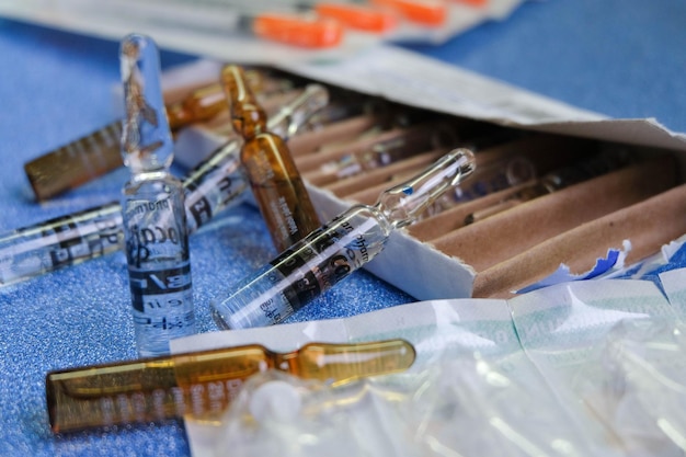 Free photo medical ampoules full of medicine and their box on a blue background