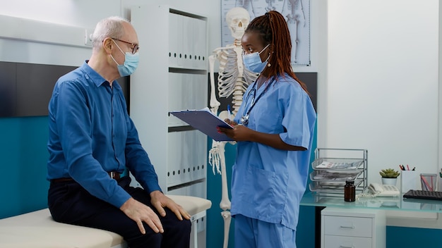 Medical assistant doing checkup consultation with old man, examining patient with disease to give medical support and treatment. Female nurse consulting person at healthcare appointment.