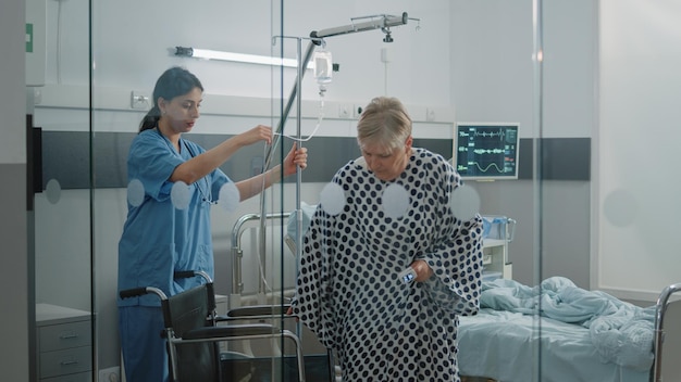 Medical assistant helping sick patient to sit in wheelchair