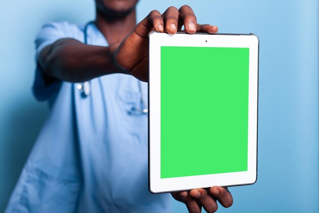 Medical assistant holding digital tablet with green screen