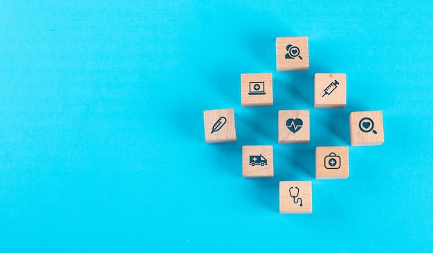 Medical check up concept with wooden blocks with icons on blue table flat lay.