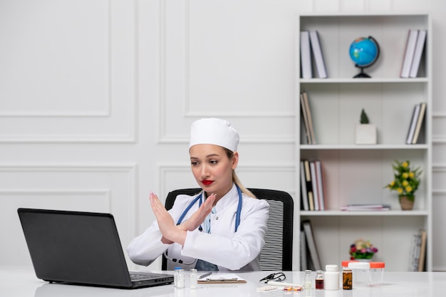 Медицинский милый милый доктор в белом лабораторном халате и шляпе с компьютером, показывающим знак окончания