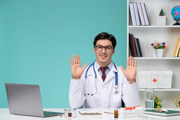 Medical cute smart doctor in lab coat working remotely on computer proud of himself