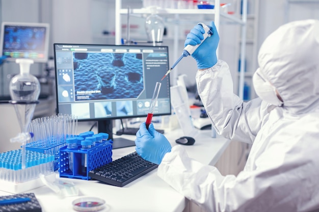 Medical engineer using dispenser to take sample of blood from test tube in lab