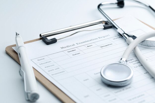 Medical examination report and stethoscope on white desktop