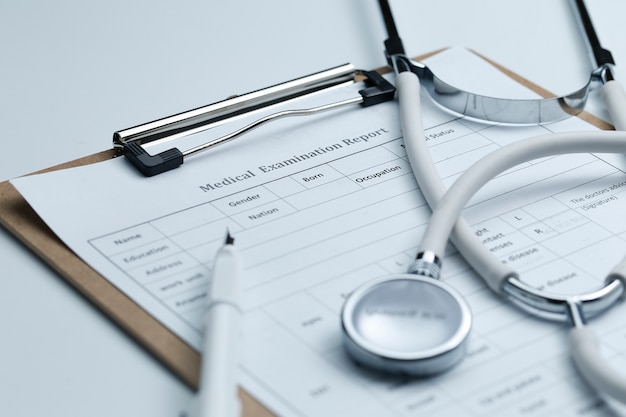 Medical examination report and stethoscope on white desktop