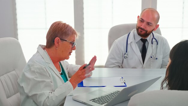 Medical experts having health seminar in hospital conference room, discussing about symptoms of patients. Clinic therapist talking with colleagues about disease for treatment development.