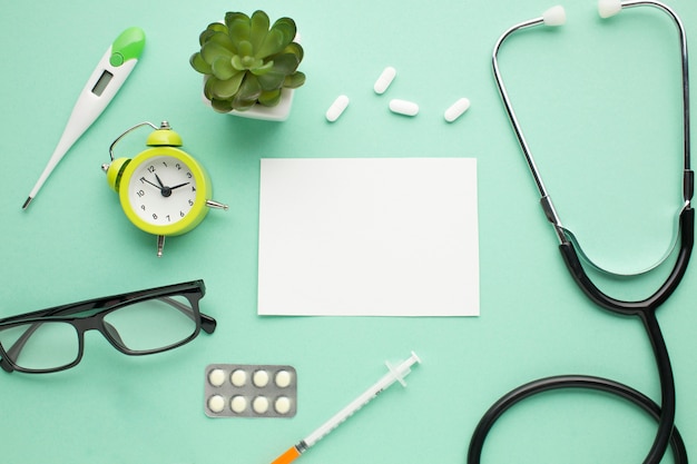 Medical instrument with alarm clock and succulent plant over plain surface