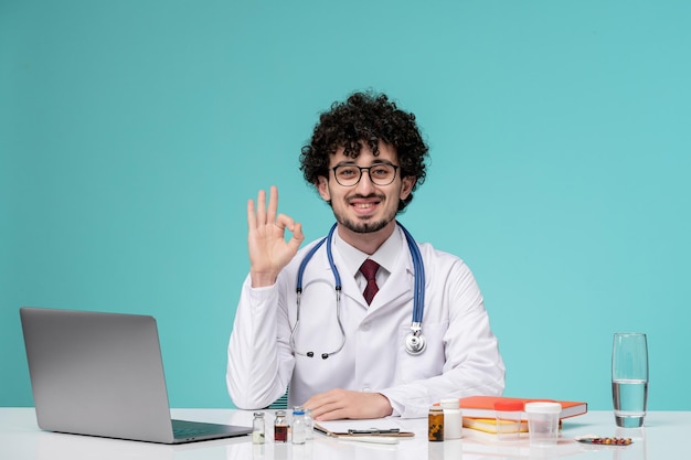 Медицинский работник в лабораторном халате молодой серьезный красивый врач, работающий на компьютере, показывает хорошо жест