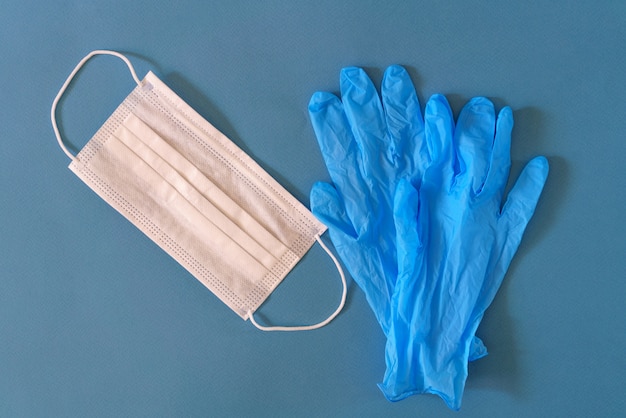 Medical mask and gloves on a blue table