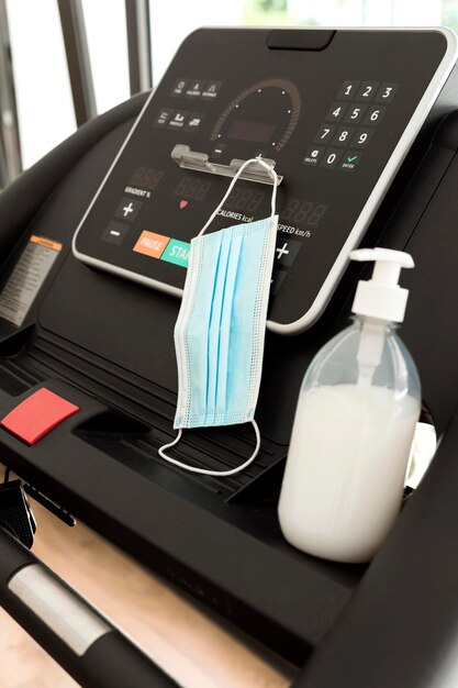 Medical mask and hand sanitizer on gym equipment