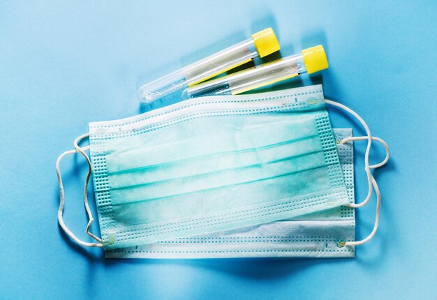 医療用​マスクコロナウイルス​保護​と​青い​背景​、​上面図​の​血液​検査管​。