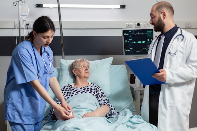 Медицинская медсестра, прикрепляющая оксиметр к пожилой женщине-пациенту