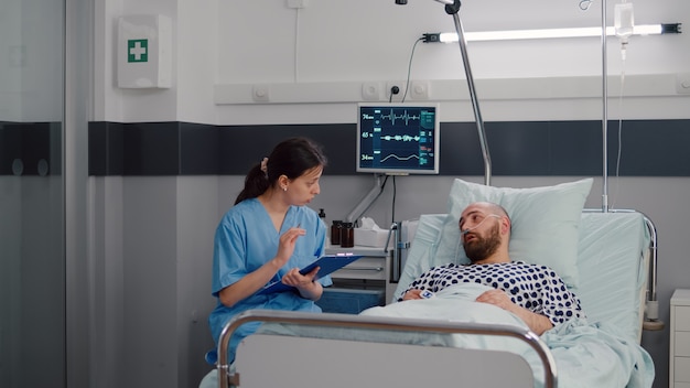 Medical nurse discussing illness treatment with hospitalized sick man