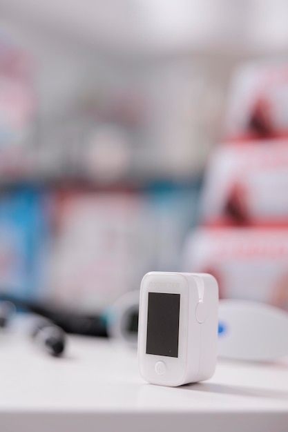 Free photo medical oximeter standing on table in empty pharmacy ready to be used by customer, digital device to measure oxygen saturation. drugstore filled with drugs, vitamins and pharmaceutical products