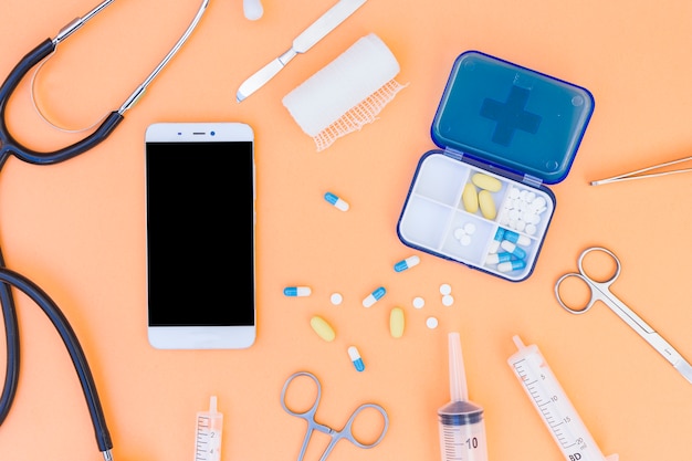 의료용 알약 상자; 청진기; 휴대 전화 및 의료 기기의 주황색 배경에