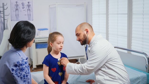 Medical practitioner listening girl heartbeat. Healthcare physician doctor specialist in medicine providing health care services radiographic treatment examination in hospital cabinet