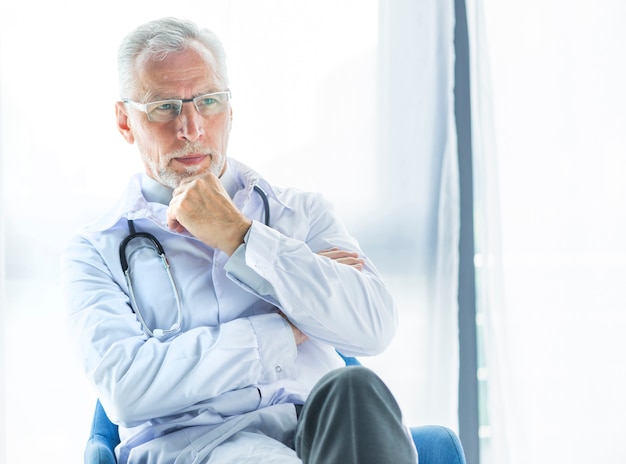 Foto gratuita medico che pensa sulla sedia