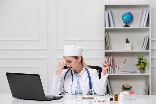 Medical pretty cute doctor in white lab coat and hat with computer very tired