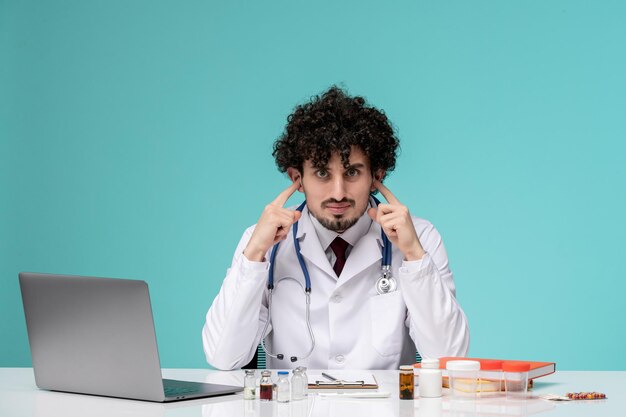 Medical remotely working on computer cute handsome doctor in lab coat covering ears