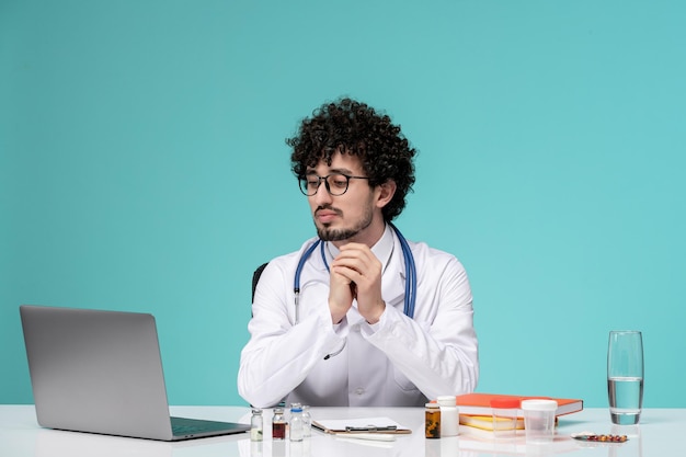 深刻な座っている白衣でコンピューターに取り組んでいる医療深刻なかわいいハンサムな医者