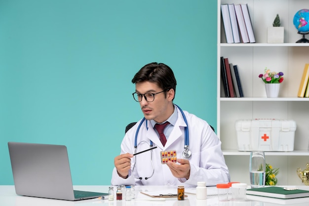 컴퓨터에서 질병을 치료하는 원격 작업을 하는 실험실 코트를 입은 의학적 진지하고 귀여운 똑똑한 의사