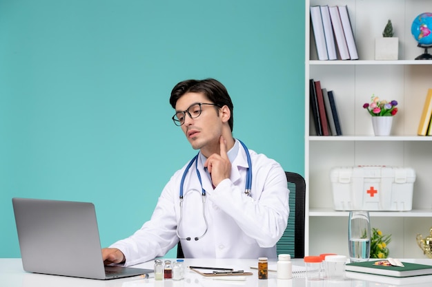 Medical serious cute smart doctor in lab coat working remotely on computer showing to throat