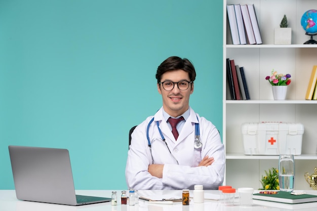 Медицинский умный молодой врач в лабораторном халате работает удаленно на компьютере, скрещивая руки