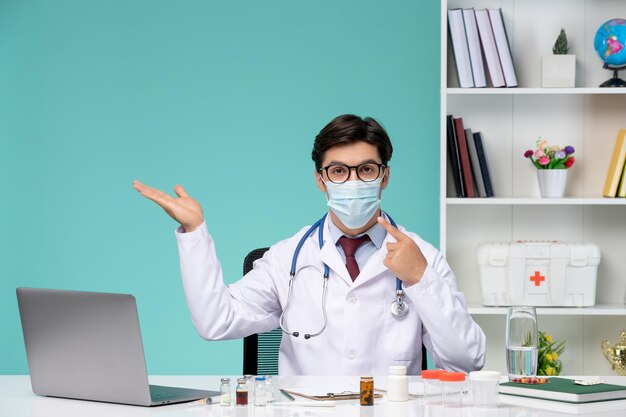 白衣を着た医療の賢い若い医者がマスクを身に着けているコンピューターでリモートで作業