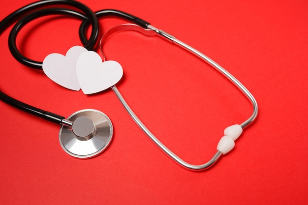 Медицинский стетоскоп и красные сердца на красном фоне для здравоохранения, медицины, лечения, образования и концепции валентина