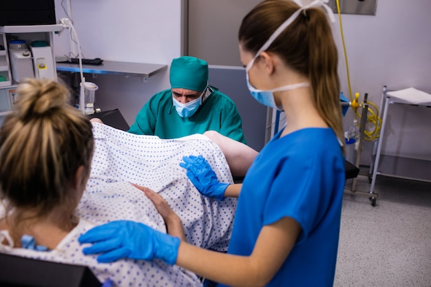 Medical team examining pregnant woman during delivery