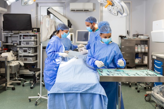 Foto gratuita gruppo medico che esegue l'operazione gruppo di chirurgo al lavoro in sala operatoria dai toni di blu operazione medica in sala operatoria presso il concetto di ospedale per la pubblicità assicurativa