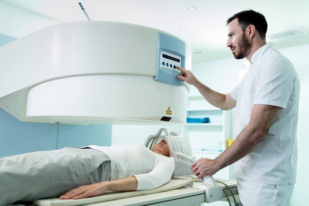 病院の女性患者の頭部MRIスキャン手順を開始する医療技術者
