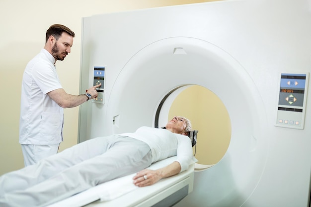 Medical technician starting MRI scan procedure of mature patient at clinic