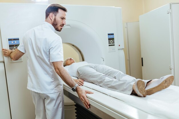 Medical technician starting MRI scanning examination of a female patient at medical clinic