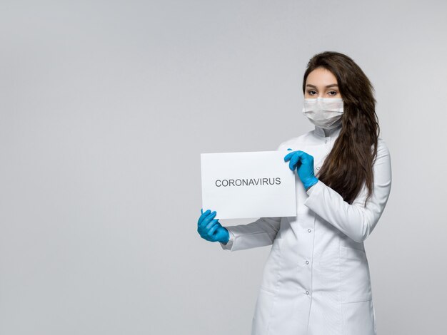 Foto gratuita lavoratore medico che tiene pezzo di carta con la parola coronavirus
