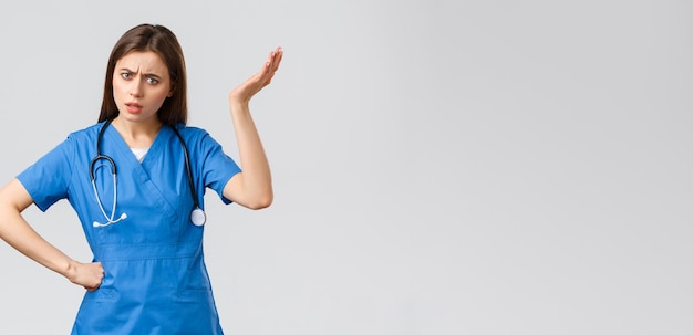 Free photo medical workers healthcare covid19 and vaccination concept frustrated and confused young female nurse pretty doctor in blue scrubs hear strange idea shrug with hand raised in nonsense