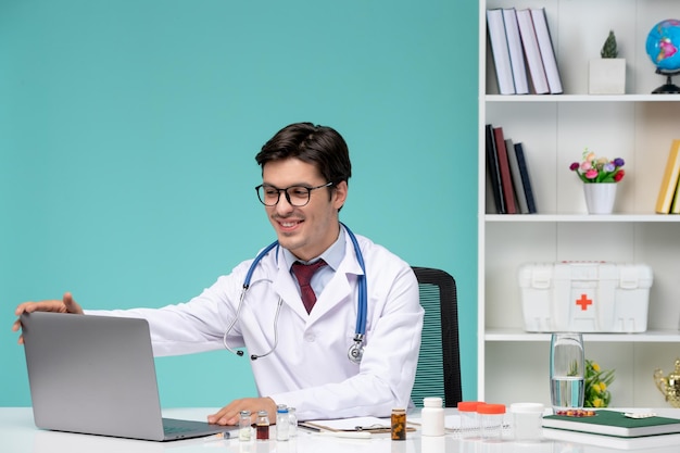 컴퓨터에서 원격으로 작업하는 의료 실험실 코트 닫는 노트북에 심각한 귀여운 똑똑한 의사
