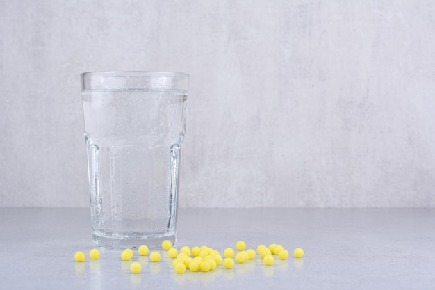 コップ一杯の水で医療用黄色の錠剤。高品質の写真