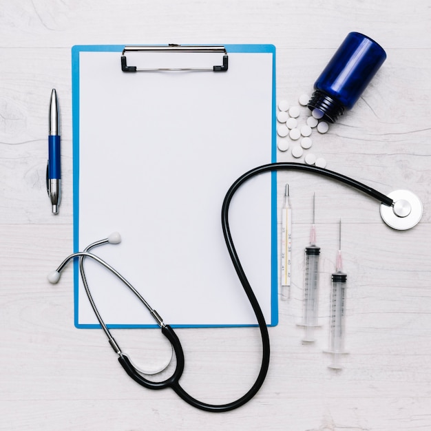 Medications and stethoscope near clipboard and pen