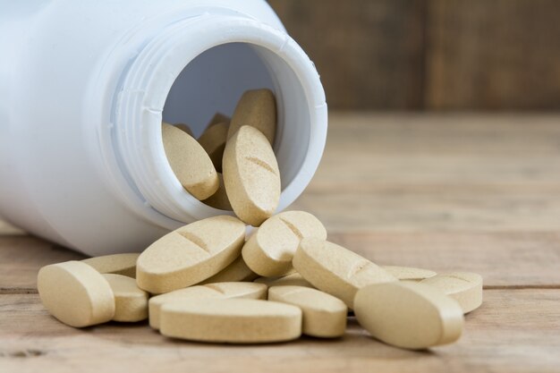 Medicine spilling out of a bottle on wood table