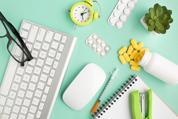 Medicines; stationery; wireless devices and alarm clock over green background