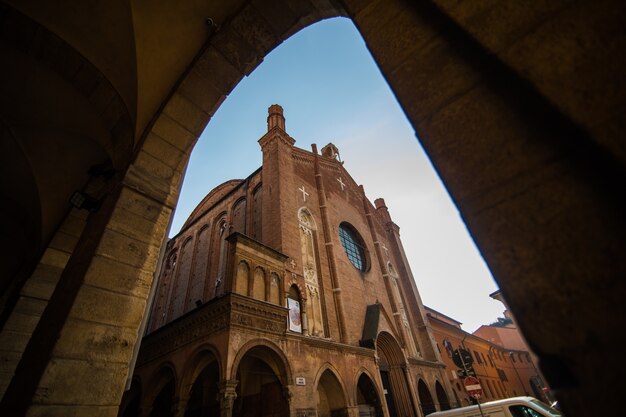 晴れた日の旧市街、ボローニャ、エミリア・ロマーニャ、イタリアの明るい色の家と中世の通りの柱廊玄関