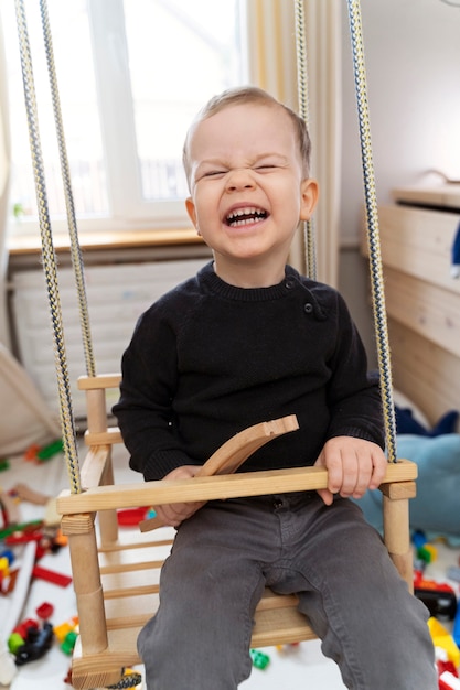 Free photo medim shot smiley kid in swing at home