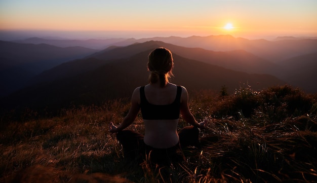 Meditating female is relaxing in mountains