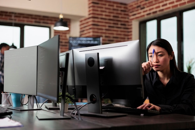 Free photo meditative asian program engineer thinking of ways to combat hacking attacks. thoughtful blockchain developer reflecting at low levels of security and how to improve mainframe defence system.